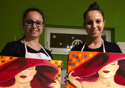 Felnőttek boldogan mutatják az élményfestésen elkészített képeiket.